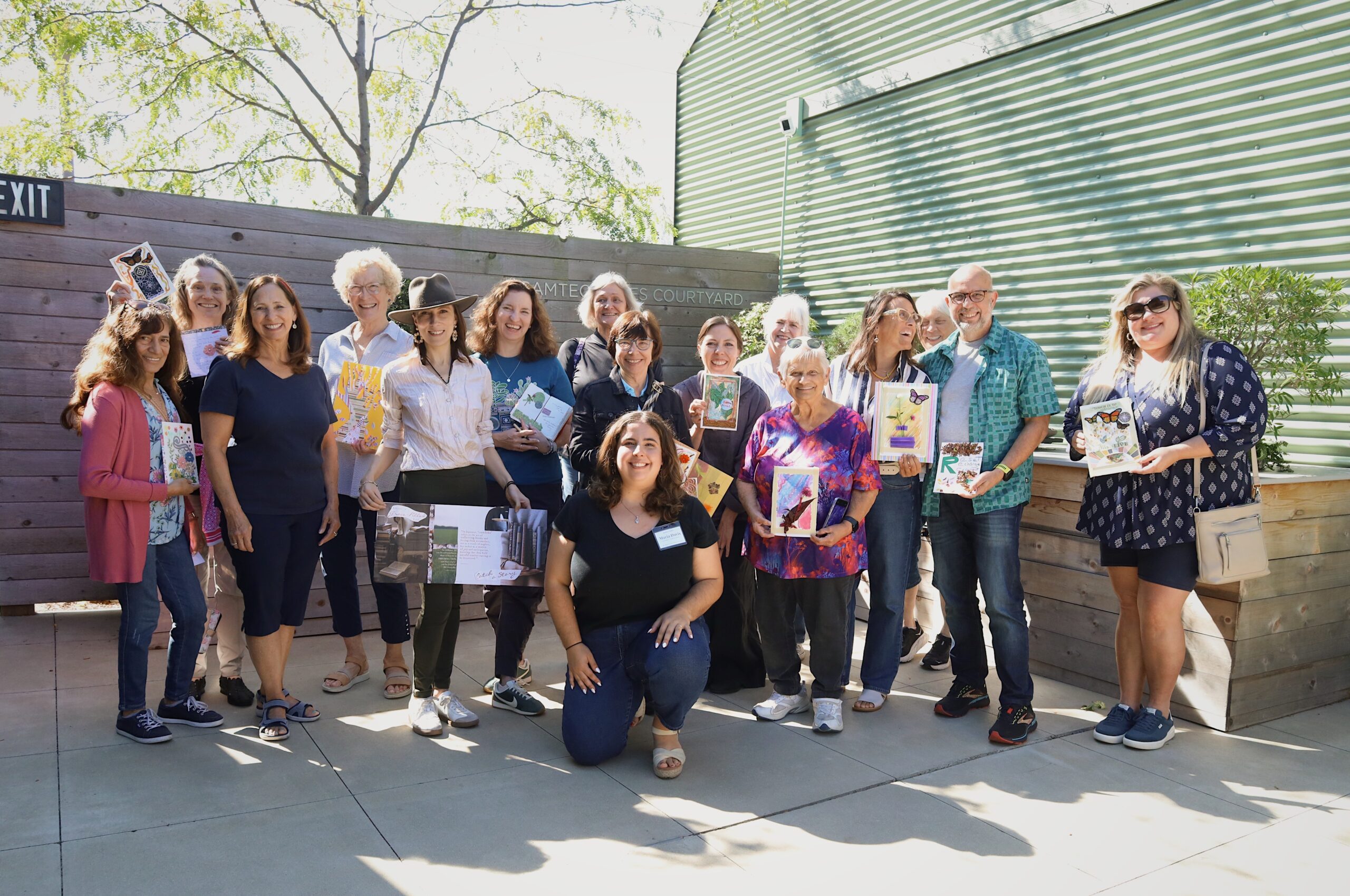 A group of women hold notebooks outside of the Waterfront Botanical Gardens